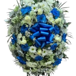 Blue and white funeral wreath on a standing easel with a large blue bow