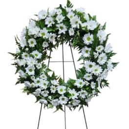 White daisy wreath on a standing easel with white ribbon bows