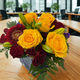Bouquet of yellow and burgundy roses with a burgundy gerbera daisy in a vase