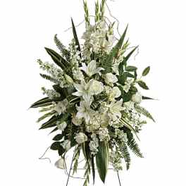 White floral standing spray on an easel with lilies and roses
