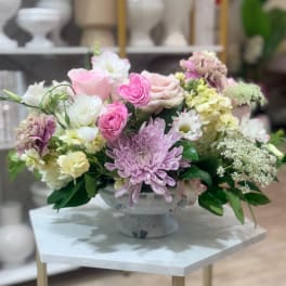 Pastel flower arrangement in a pedestal vase with pink, white, and lavender blooms