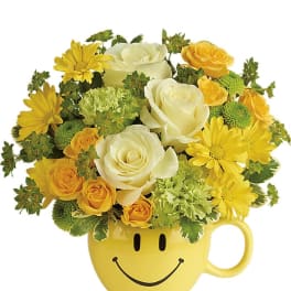 Arrangement of white and yellow roses and daisies in a yellow smiley-face mug