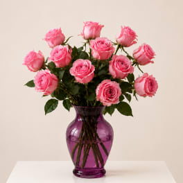 Pink roses arranged in a purple glass vase