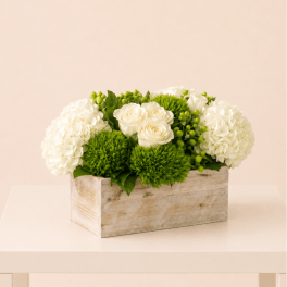 White roses and hydrangeas in a rustic wooden box with green pom-pom flowers