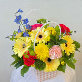 Mixed flower basket with gerbera daisies, carnations, and blue delphinium