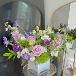Lavender and white floral arrangement in a square glass vase