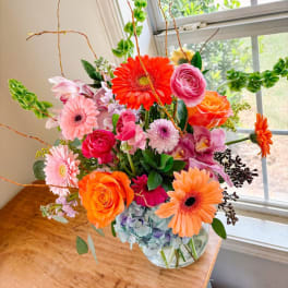 Colorful mixed bouquet in a clear glass vase with gerbera daisies and roses