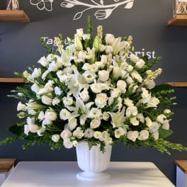 Large white floral arrangement in a white pedestal vase