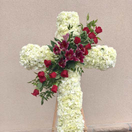 Floral cross on an easel with white blooms and red roses