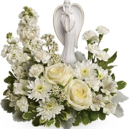 White sympathy arrangement with roses, carnations, mums, and an angel figurine in the center