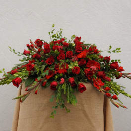 Large red rose arrangement with mixed greenery on a draped stand