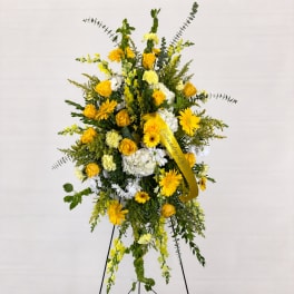 Tall yellow and white floral standing spray on an easel with a ribbon