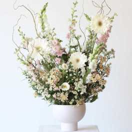 Tall floral arrangement with white daisies and pink blooms in a white vase