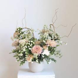 Blush and white floral arrangement in a white vase with curly branches