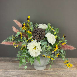 White carnations and yellow daisies in a gray vase with dried lotus pod