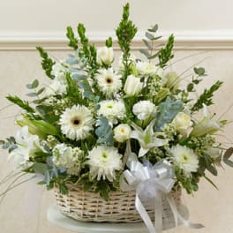 White and green sympathy basket with roses, lilies, gerbera daisies, and mums accented with a white ribbon bow