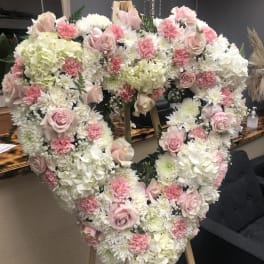 Heart-shaped floral arrangement with pink and white roses and carnations