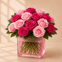 Pink and hot pink roses arranged in a square pink glass vase