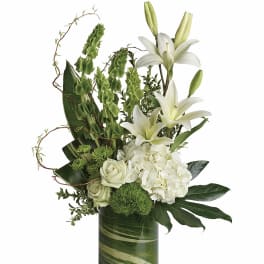 White lilies and roses arranged in a green glass vase