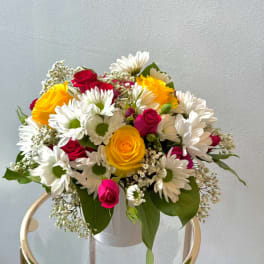 Bouquet of yellow and red roses with white daisies in a white vase