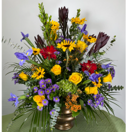 Colorful mixed bouquet in a bronze vase with yellow, purple, red, and dark blooms