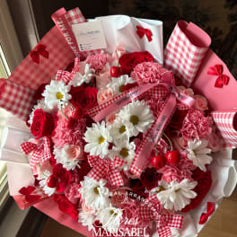 Pink and red bouquet with roses, carnations, and daisies wrapped in gingham paper