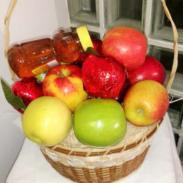 Fruit basket with apples and wrapped candies in a wicker basket