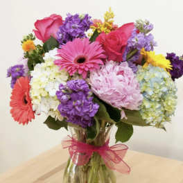 Mixed bouquet of pink, purple, yellow, and white flowers in a glass vase