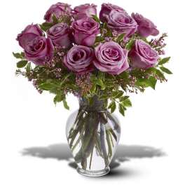 Purple roses arranged in a clear glass vase