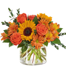 Orange roses and sunflowers in a clear glass vase