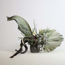 Modern succulent arrangement in a small vase with large dried leaves