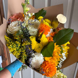 Mixed bouquet of roses, chrysanthemums, and carnations wrapped in brown paper