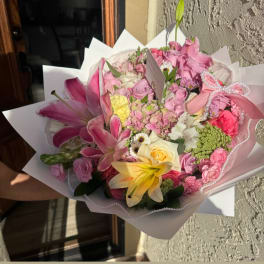 Pink and yellow mixed flower bouquet wrapped in white paper