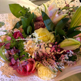 Mixed bouquet of roses and lilies in pastel wrapping