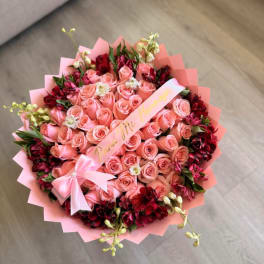 Pink rose bouquet with red accent flowers and a ribbon