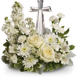 White floral arrangement with roses, daisies, and a silver cross