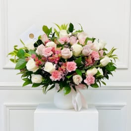 Pink and white bouquet in a white vase with a ribbon