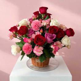 Mixed bouquet of red, pink, and white roses in a wicker basket