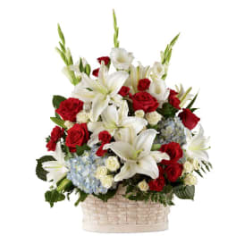 Tall basket arrangement with white lilies, red roses, white roses, and light blue hydrangeas