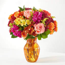 Mixed bouquet of roses, chrysanthemums, and alstroemeria in an amber glass vase