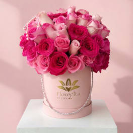Pink and white roses arranged in a round hatbox with a pearl strand