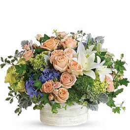 Peach roses and white lilies in a low white container