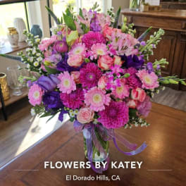 Pink and purple mixed flower bouquet in a glass vase with ribbon