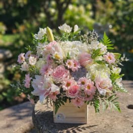 Pink and white mixed flower arrangement in a wooden box