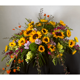Large arrangement of sunflowers and mixed blooms in a dark container
