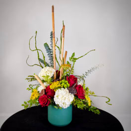 Tall floral arrangement in a teal vase with red, white, and yellow blooms