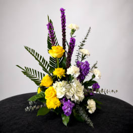 Yellow, white, and purple floral arrangement in a low container