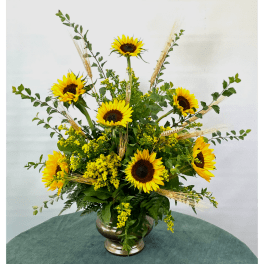 Sunflower arrangement in a silver vase with wheat accents