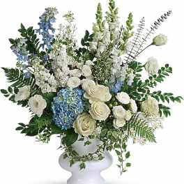 White and blue floral arrangement in a white pedestal vase