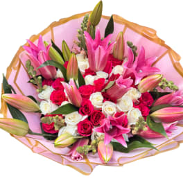 Bouquet of pink lilies and red and white roses wrapped in pink paper